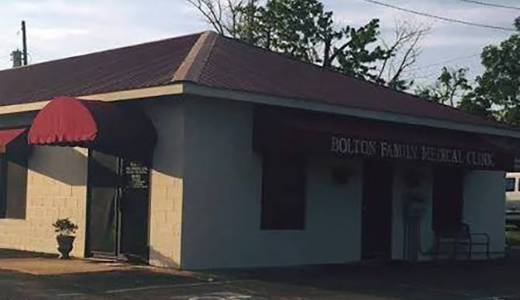 A small building with a red awning and a sign reading Bolton Family Medical Clinic.