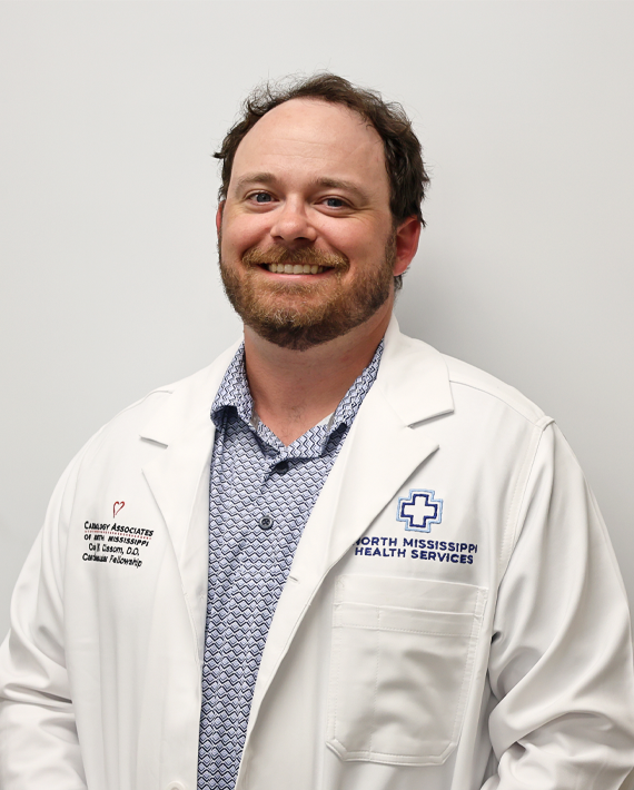 A person wearing a medical coat featuring logos of healthcare services against a light-colored background.