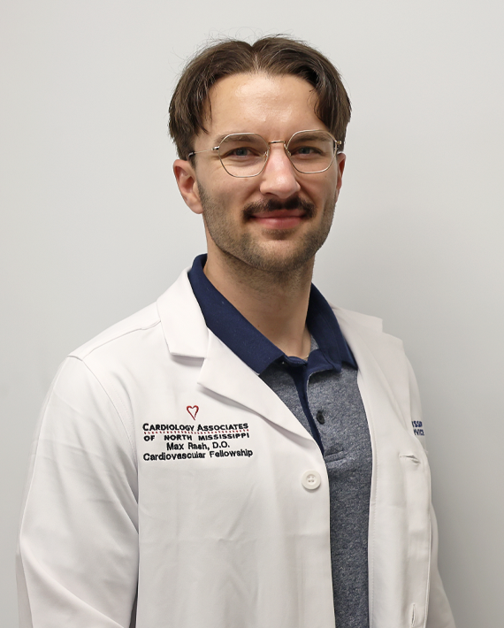 Man wearing glasses and a white coat poses in front of a plain background.